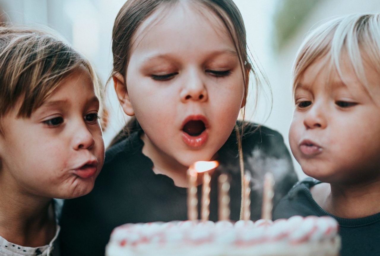 Kinder beim Auspusten von Kerzen auf einem Geburtstagskuchen